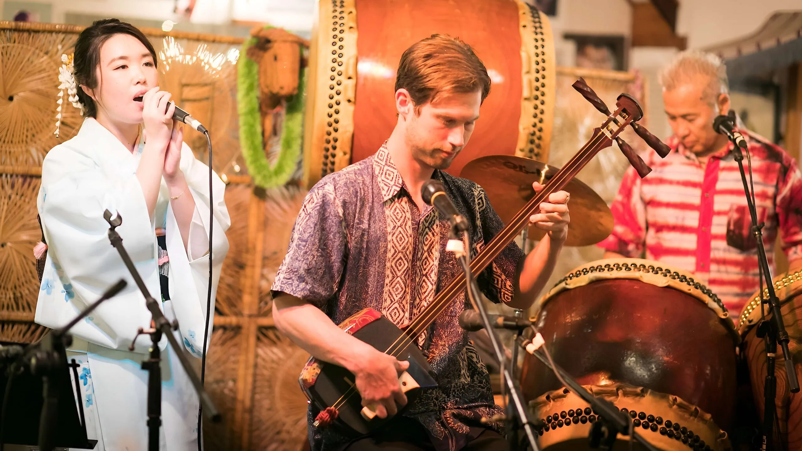 Kyle performing with a vocalist and taiko drummers