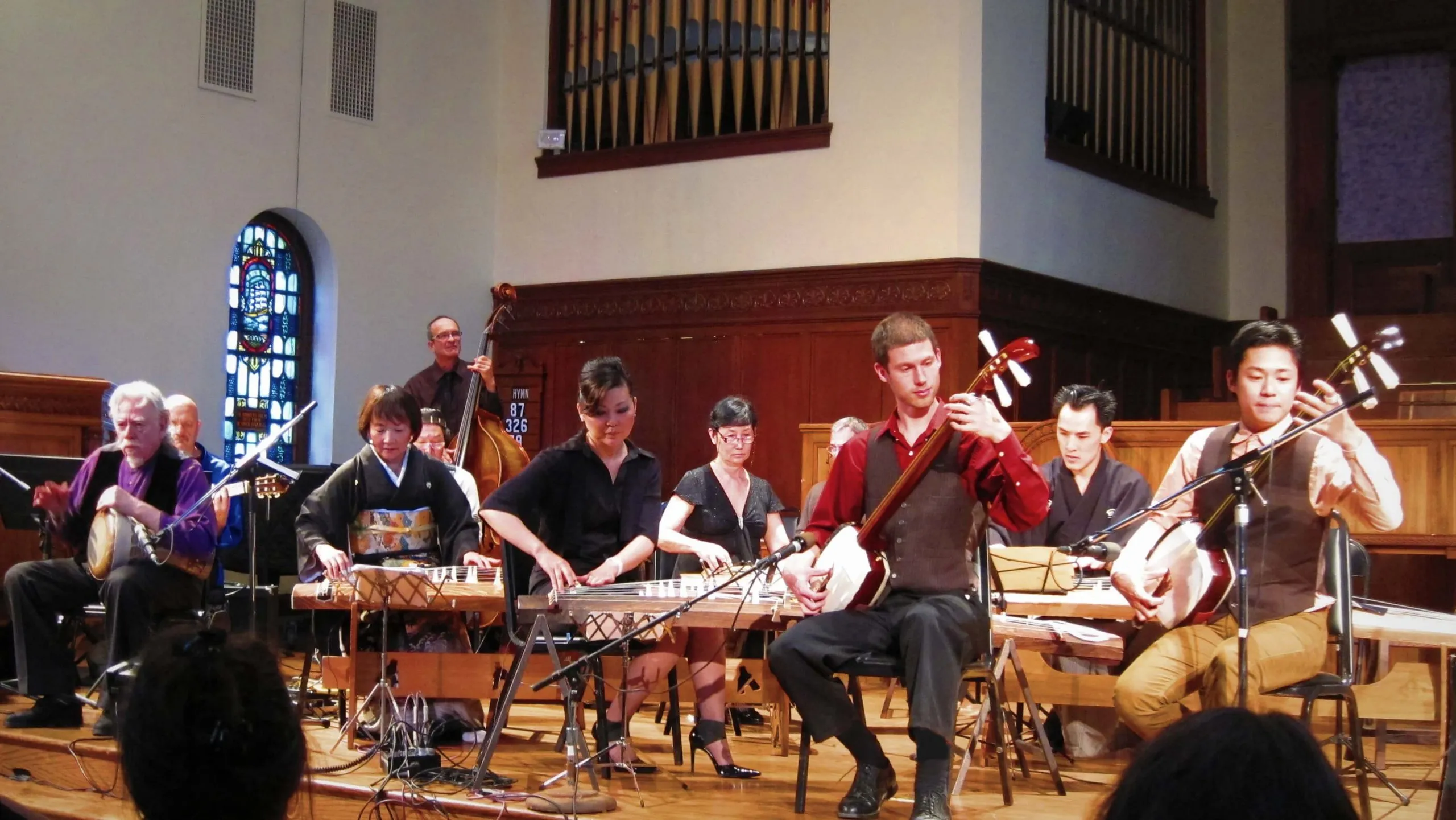 Kyle performing with an ensemble of shamisen and koto players in a concert hall